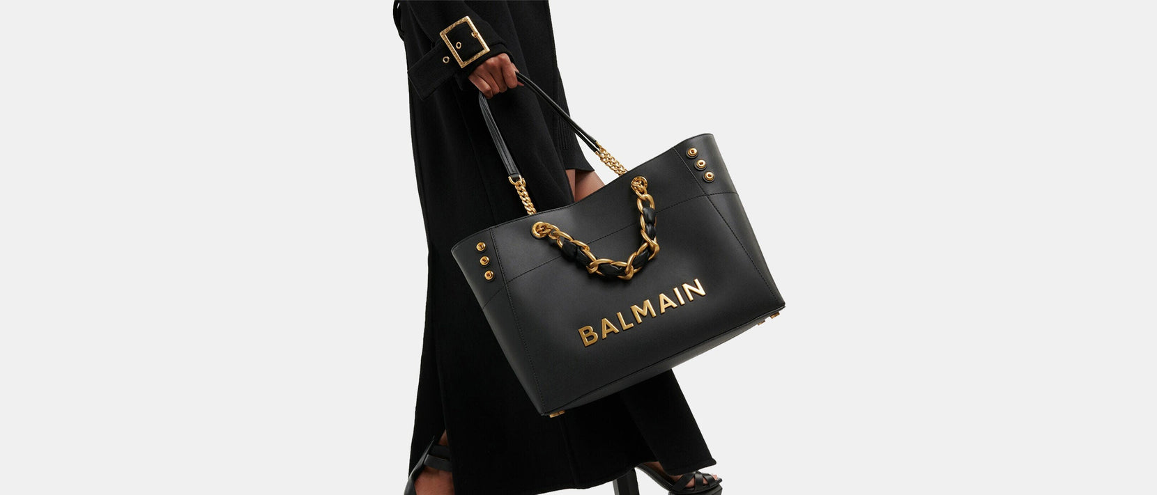 Close up of woman holding Balmain black leather tote with gold hardware