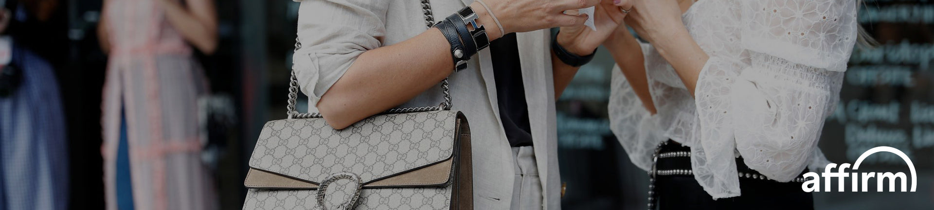 Person holding a Gucci chain strap handbag with blurred background