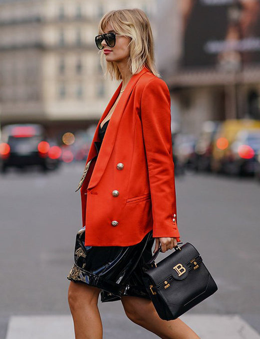 Woman carrying top handle black leather Balmain handbag with gold hardware and details