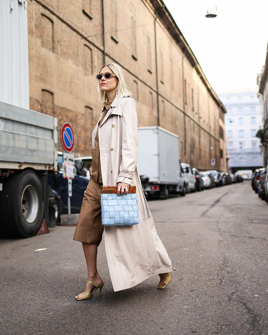 Stylish woman walking across street with baby blue Bottega Veneta bag. 