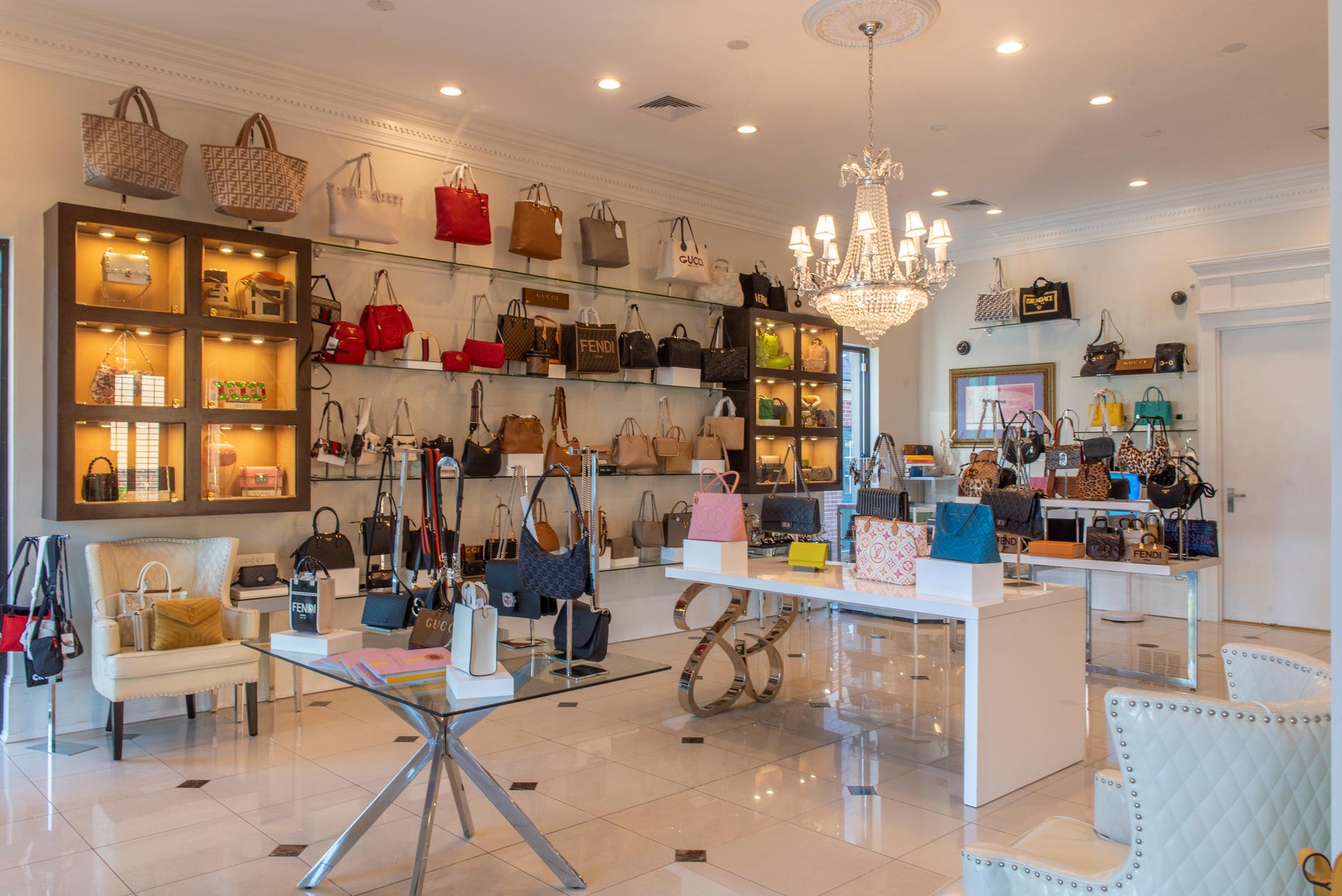 Interior of a high-end Queen Bee of Beverly Hills handbag store with various handbags displayed on shelves and tables based in Huntsville, Alabama