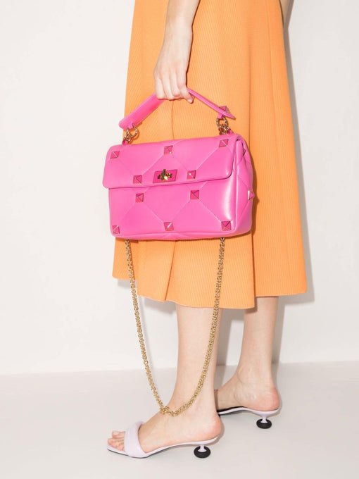 Woman holding Valentino Pink Roman Stud handbag 