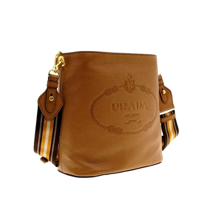 Prada Vitello Phenix Bucket Crossbody Bag Caramel Brown Web Strap available at Queen Bee of Beverly Hills